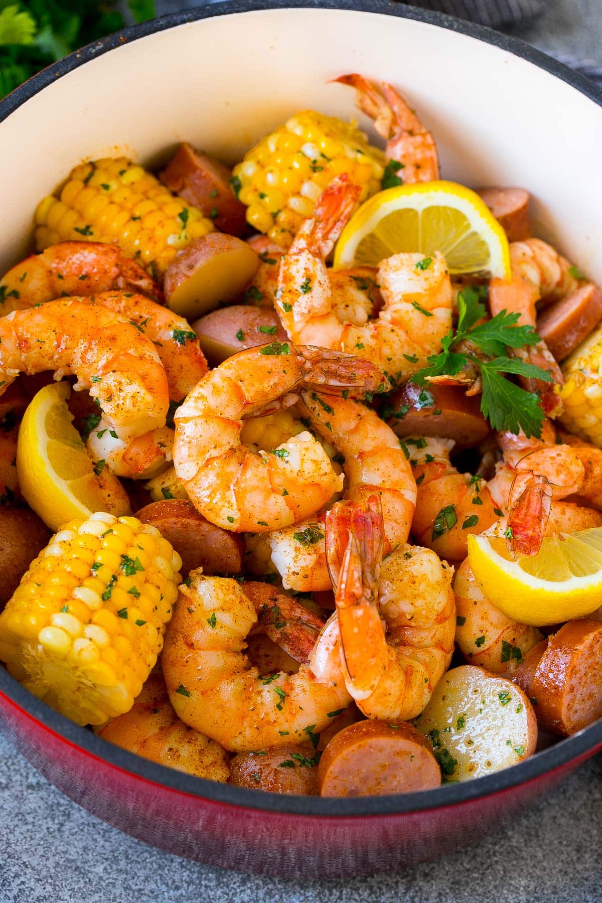 A shrimp boil with potatoes and corn in a red pot.