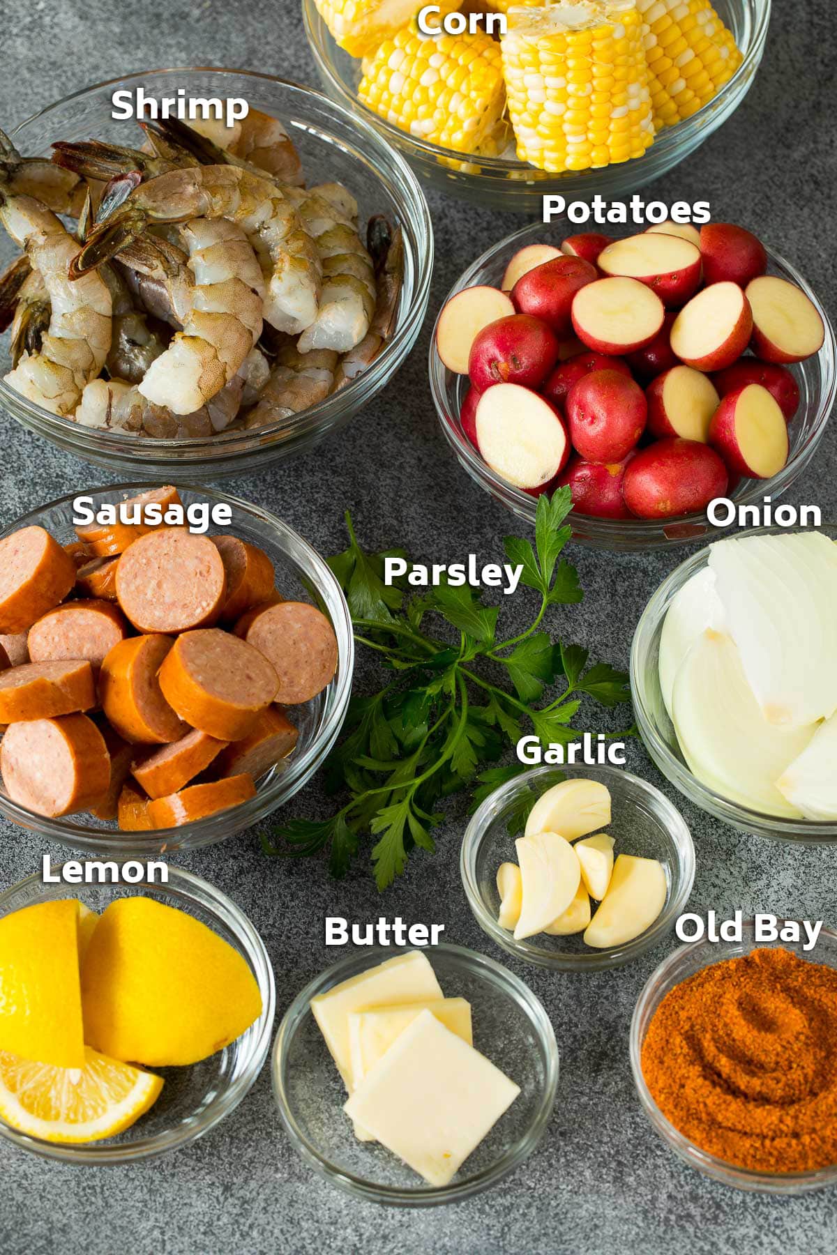 Bowls of ingredients including shrimp, corn, potatoes, sausage and seasonings.
