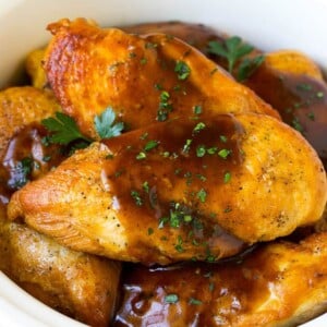 Slow cooker chicken breasts topped with gravy and parsley.