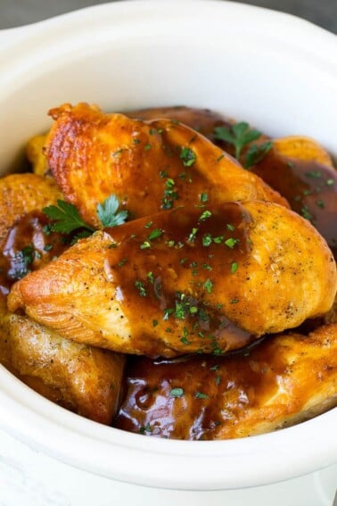 Slow cooker chicken breasts topped with gravy and parsley.