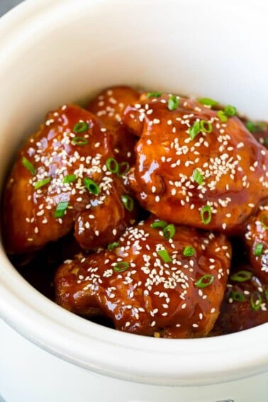 Slow cooker chicken thighs garnished with sesame seeds and green onions.