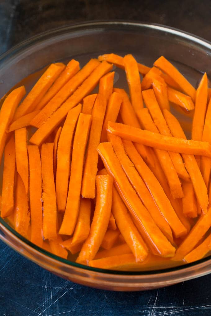 Strips of sweet potato in a bowl of water.
