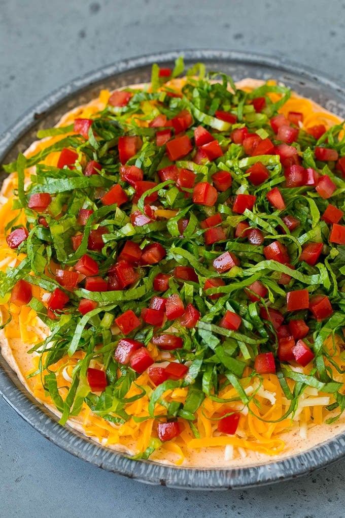 Lettuce and tomato on top of shredded cheese and a creamy dip base.