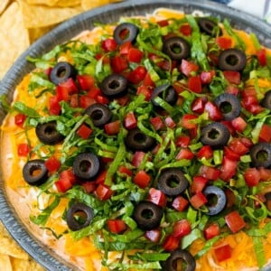 Taco dip with layers of seasoned cream cheese, lettuce, tomato, shredded cheese and olives.