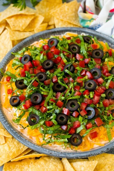 Taco dip with layers of seasoned cream cheese, lettuce, tomato, shredded cheese and olives.
