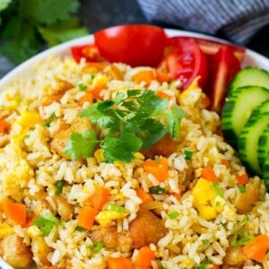 A plate of Thai fried rice garnished with cucumbers and tomatoes.