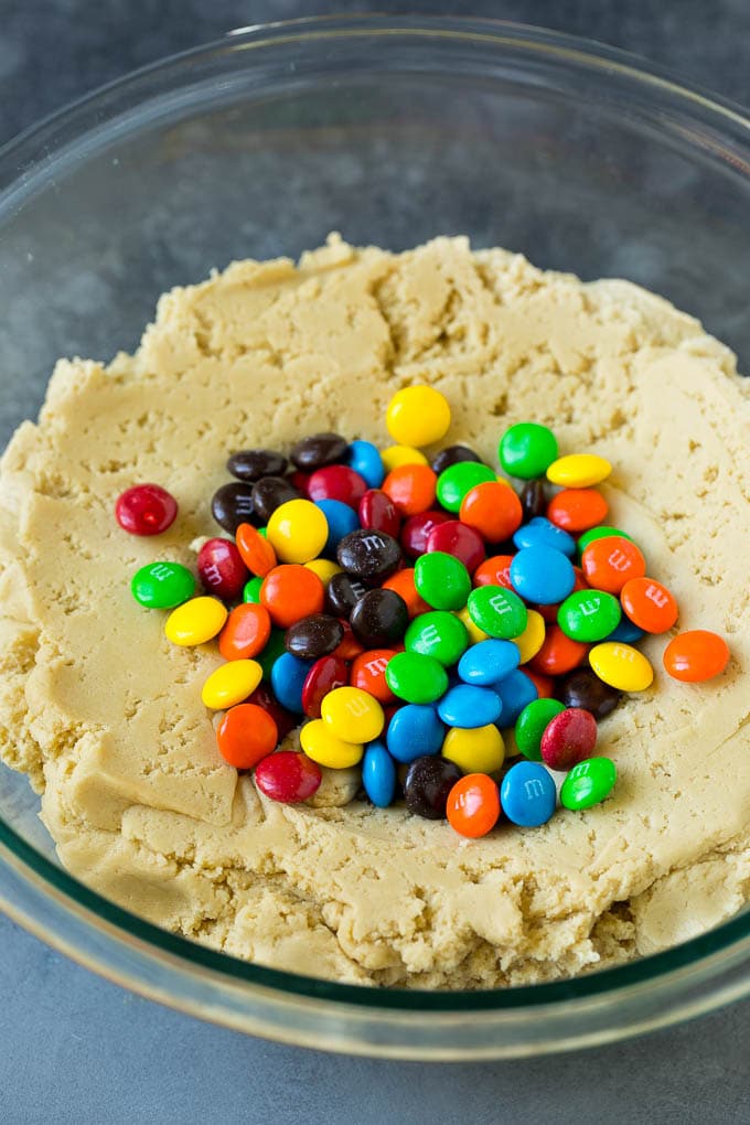 A bowl of cookie dough with chocolate candies in it.
