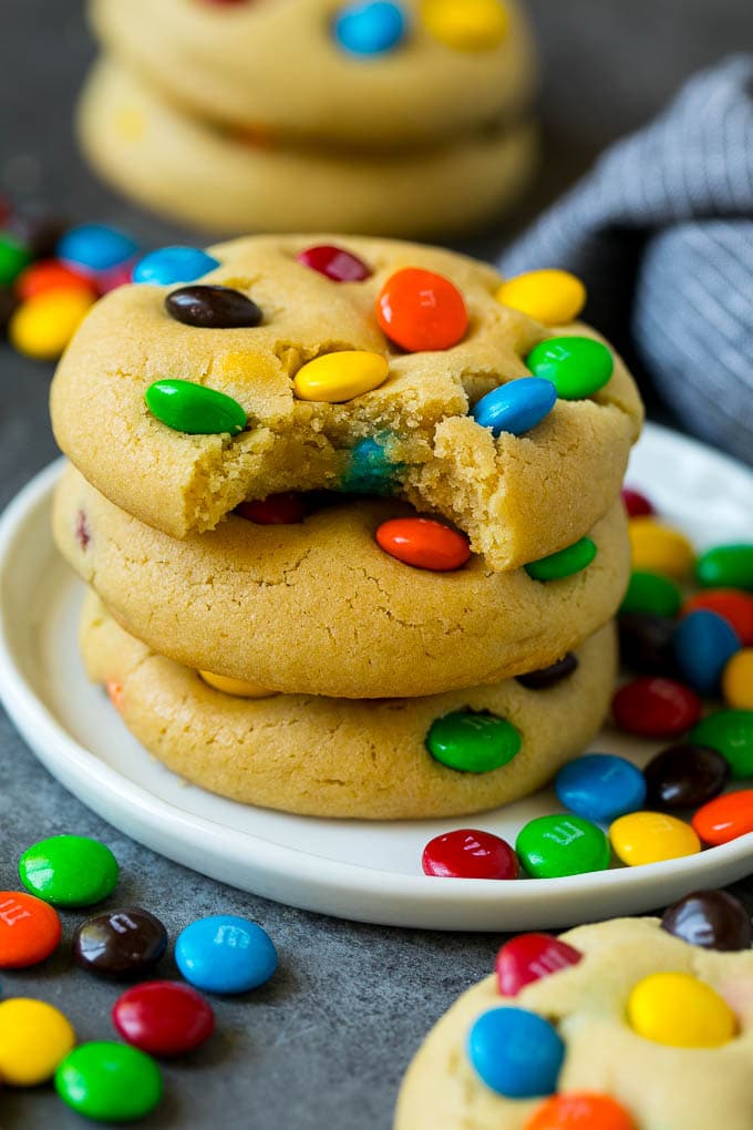 A stack of M&M cookies with a bite taken out of one.