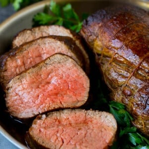 Sliced beef tenderloin garnished with fresh parsley.