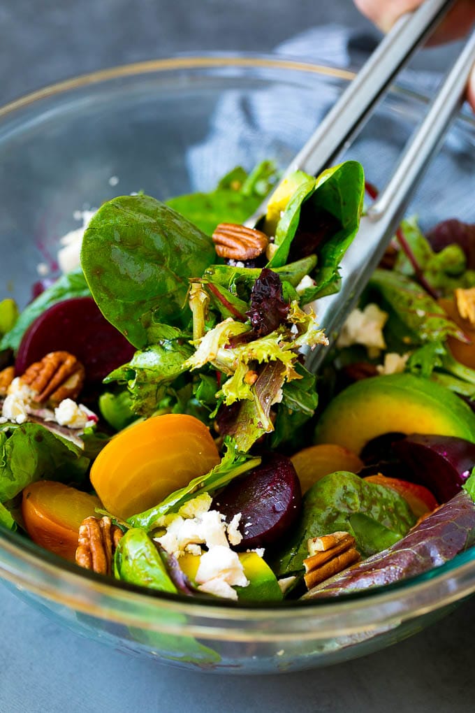 Tongs serving a portion of beet salad tossed in balsamic dressing.