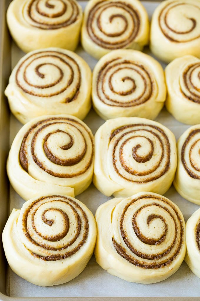 Rolls of dough and filling rising on a sheet pan.