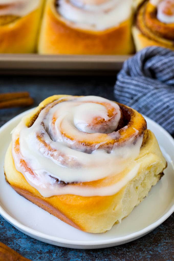 A frosted cinnamon bun on a serving plate.