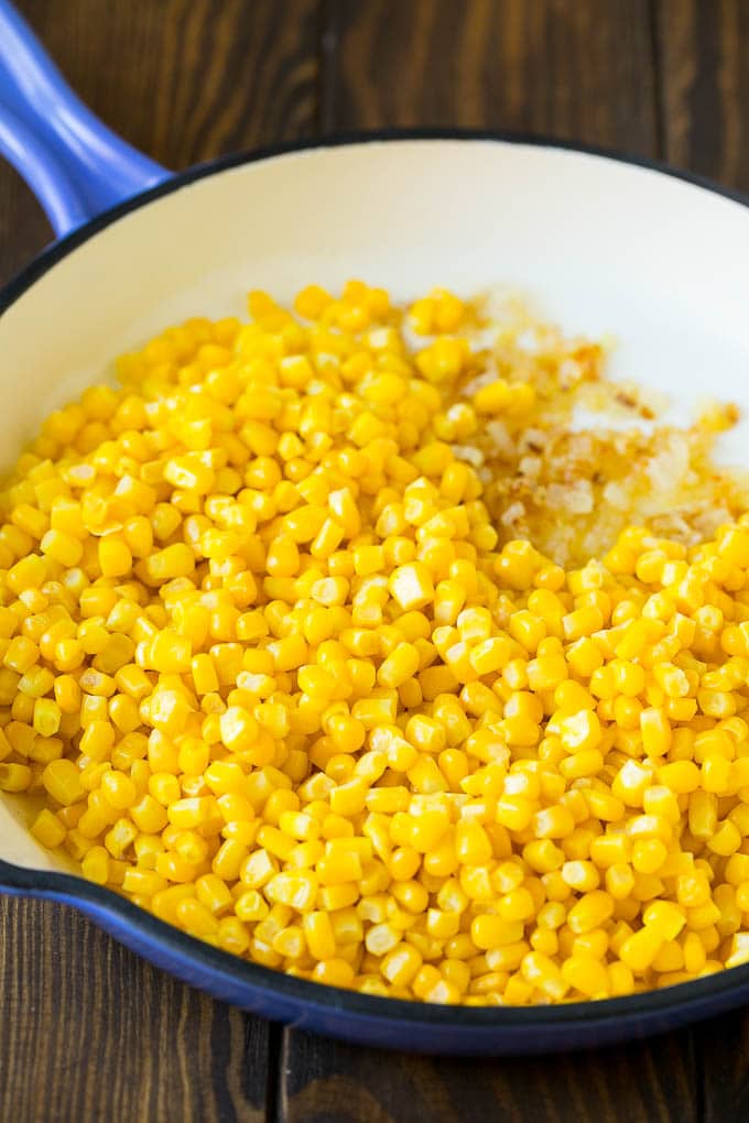 Corn and sauteed onions in a pan.