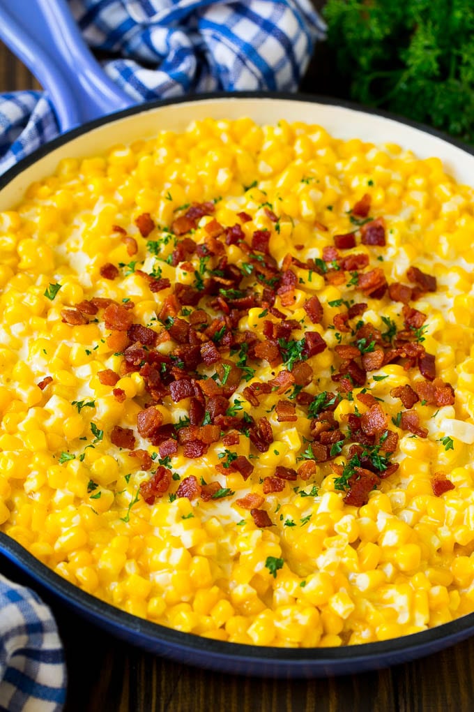 Creamed corn in a pan with bacon and parsley.