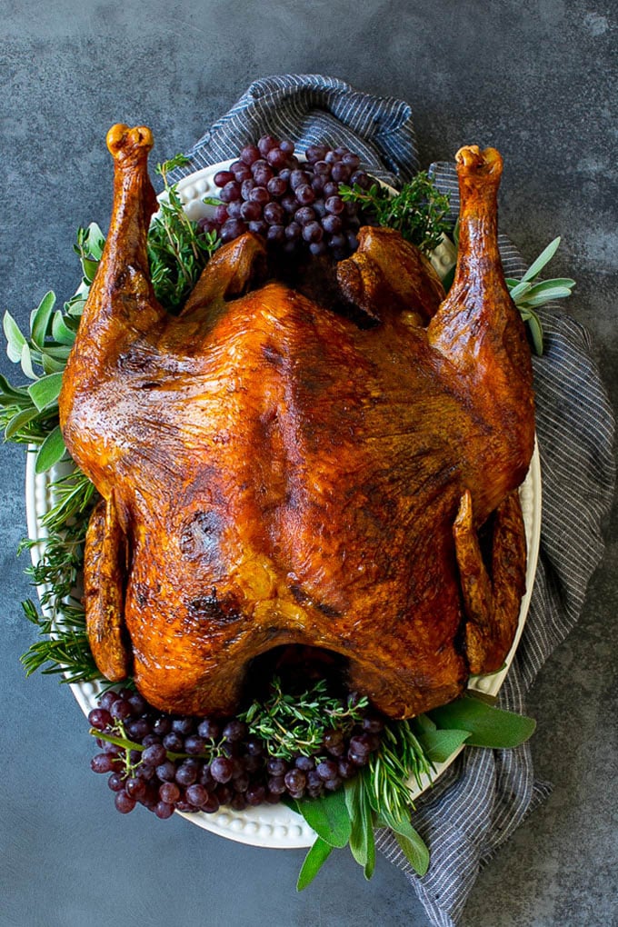 A deep fried turkey garnished with grapes and fresh herbs.