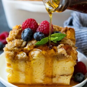 A piece of french toast casserole with syrup being poured over the top.