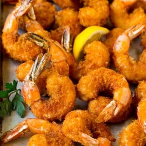 Fried shrimp on a sheet pan garnished with parsley and lemon.