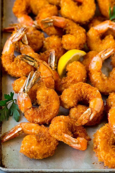 Fried shrimp on a sheet pan garnished with parsley and lemon.