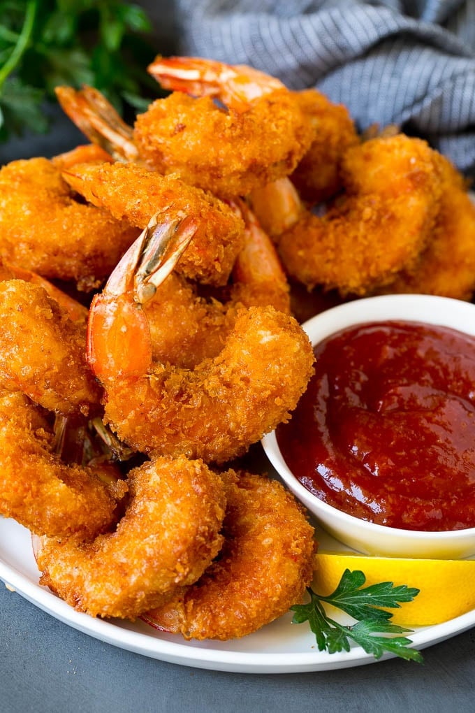 A plate of fried shrimp served with cocktail sauce.