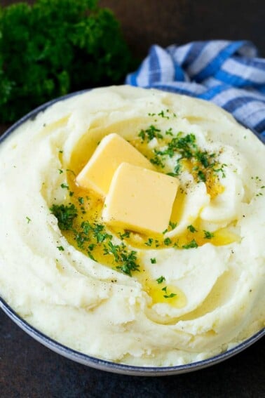 Garlic mashed potatoes topped with pats of butter and parsley.