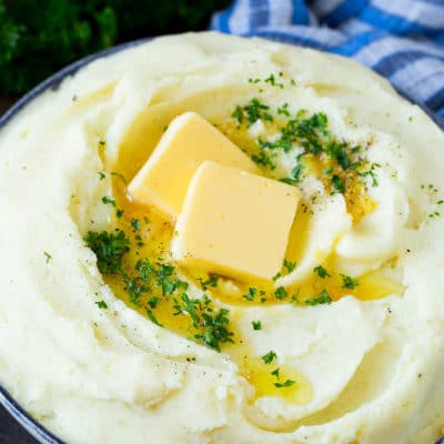Garlic mashed potatoes topped with pats of butter and parsley.