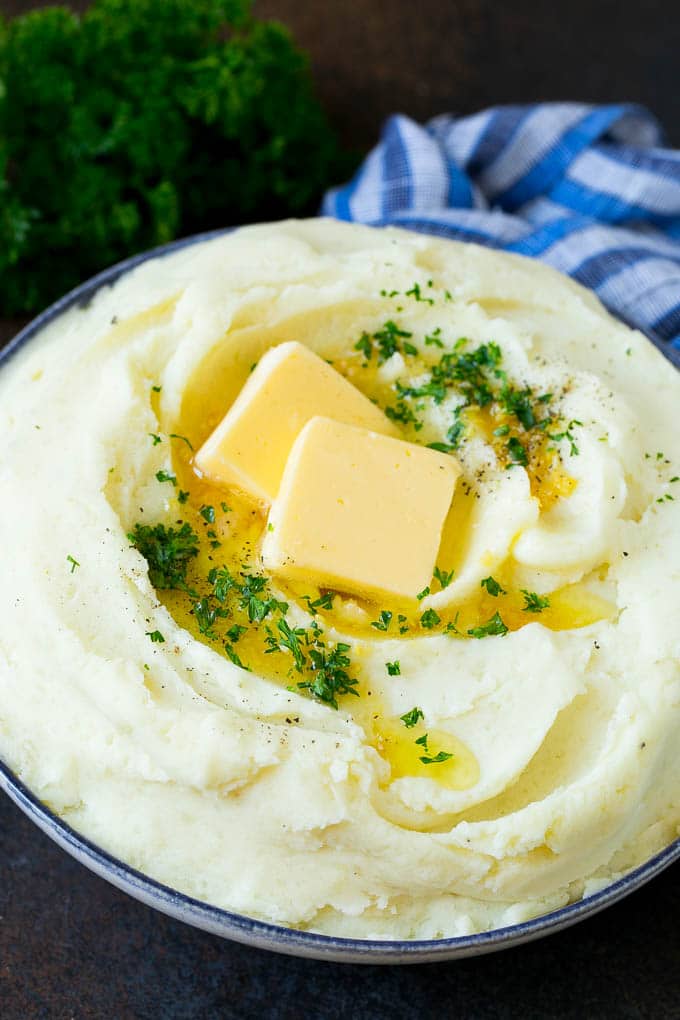 Garlic mashed potatoes topped with pats of butter and parsley.