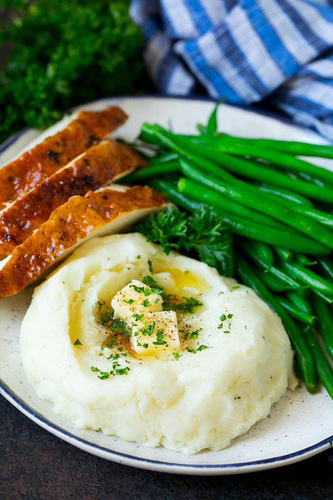 A plate with garlic mashed potatoes, green beans and sliced turkey.