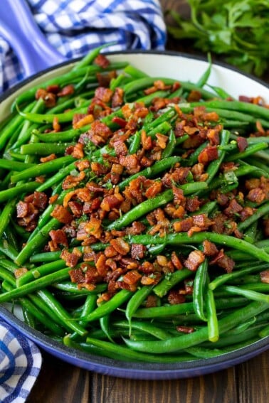 Green beans with bacon in a skillet, topped with parsley.