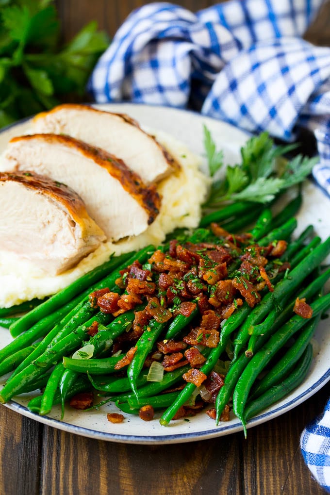Green beans with bacon served alongside turkey and mashed potatoes.