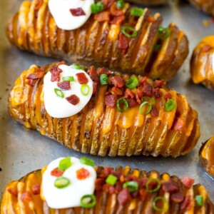 Hasselback potatoes filled with melted cheese, then topped with bacon, sour cream and green onions.