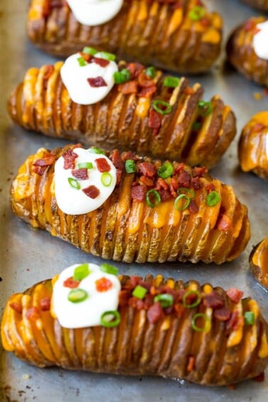 Hasselback potatoes filled with melted cheese, then topped with bacon, sour cream and green onions.