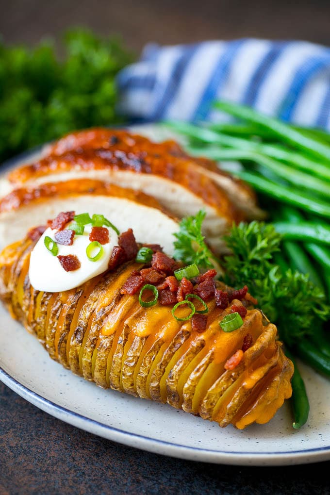 Hasselback potatoes on a plate, served with turkey and green beans.