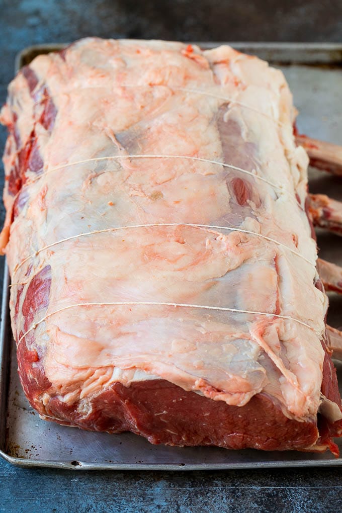 A tied standing rib roast on a sheet pan.