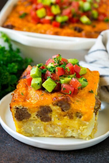A slice of sausage egg casserole with a garnish of fresh tomatoes.
