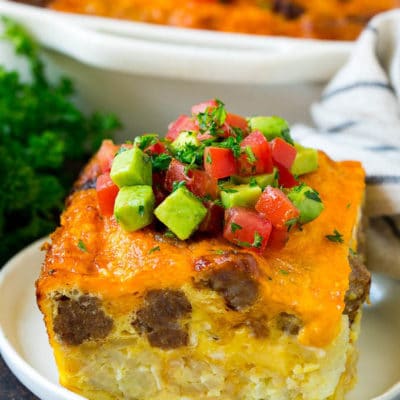 A slice of sausage egg casserole with a garnish of fresh tomatoes.