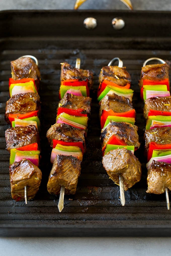 Beef skewers cooking on a grill pan.