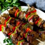 Shish kabob made with beef, peppers and onions on a serving plate.