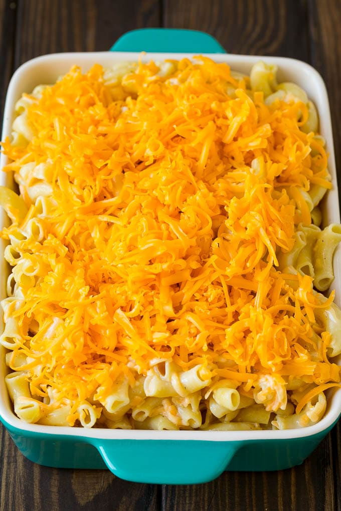 A dish full of macaroni topped with shredded cheese.