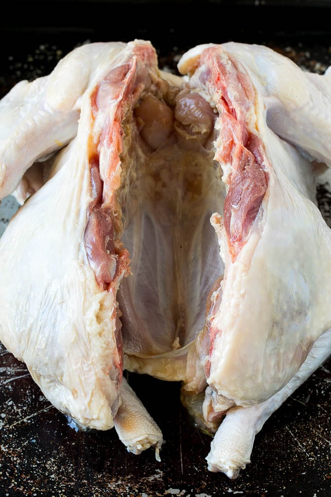 A raw turkey with the backbone cut out.