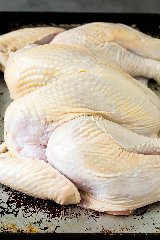 A flattened whole turkey on a sheet pan.