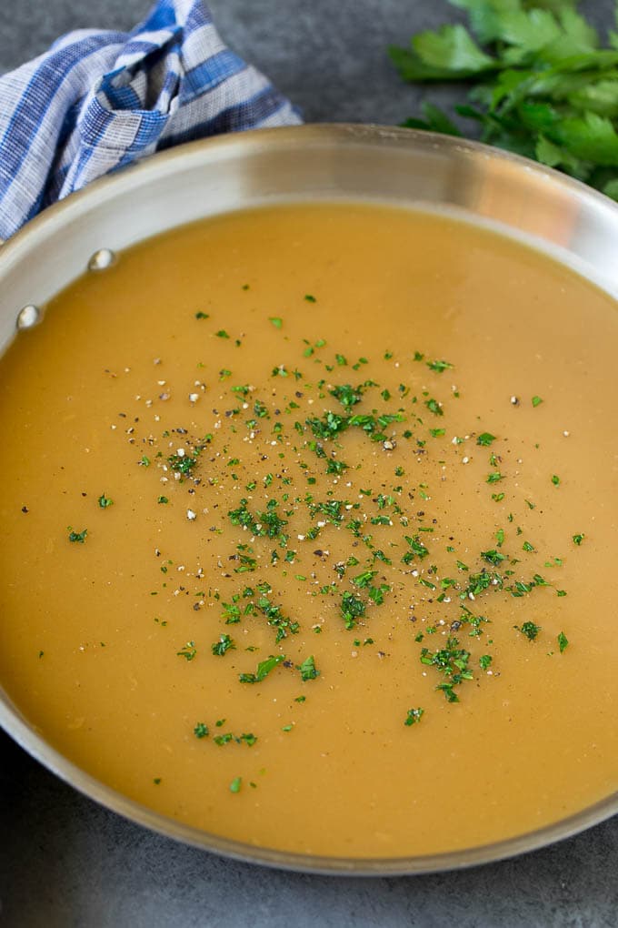 A pan of gravy topped with parsley and cracked pepper.