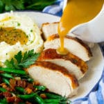 Turkey gravy being poured over sliced turkey breast.