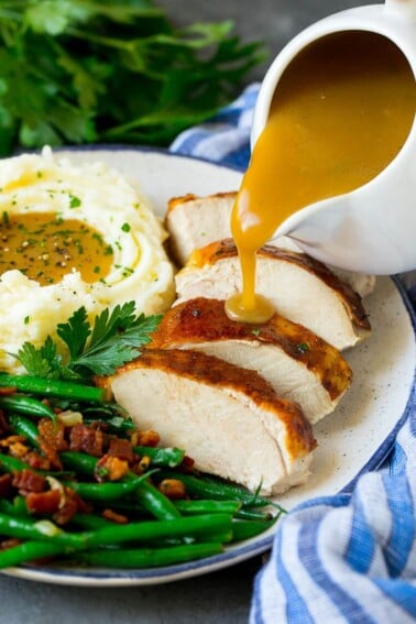 Turkey gravy being poured over sliced turkey breast.