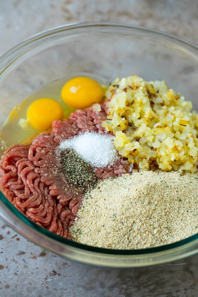 Ground beef, breadcrumbs, eggs, seasonings and onions in a mixing bowl.