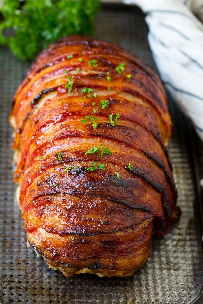 Meatloaf wrapped in slices of bacon and baked, then topped with parsley.