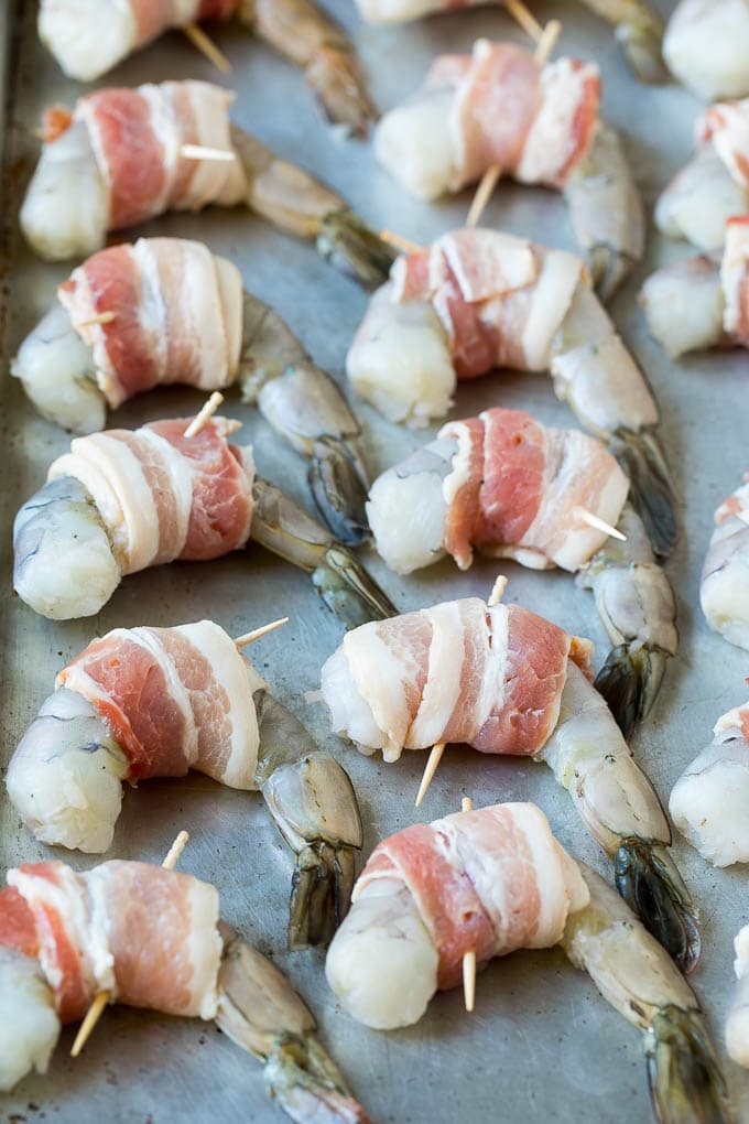 Raw shrimp on a sheet pan wrapped in bacon.