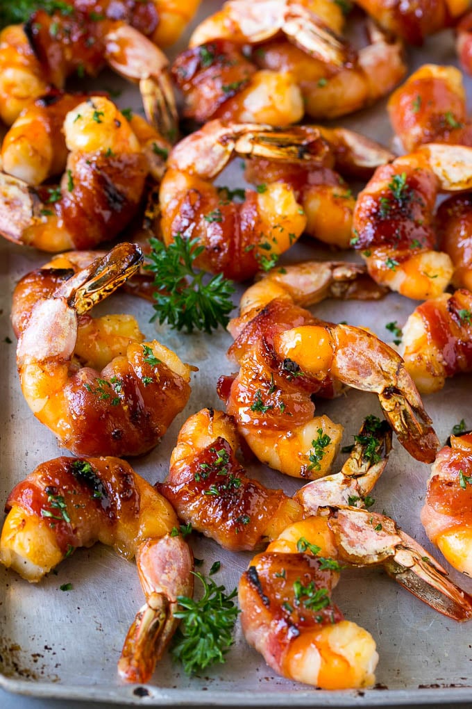Bacon wrapped shrimp in a sweet and savory glaze, garnished with parsley.