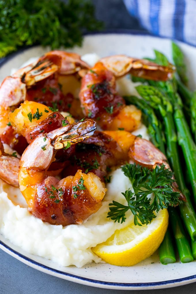 Bacon wrapped shrimp served over mashed potatoes with green beans.