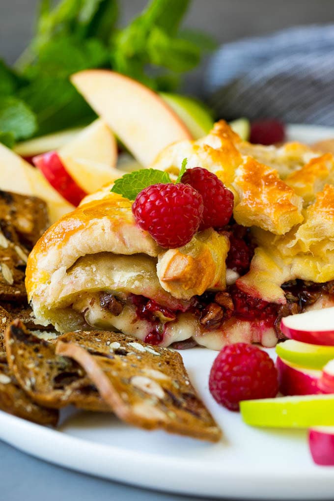 A cross section of baked brie filled with raspberries and pecans.