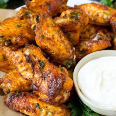 A plate of baked chicken wings served with ranch dip.